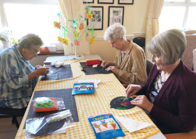 Residents at Silverpoint Court sitting around a table making Easter crafts