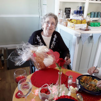 Lady resident, sitting at a Valentines decorated table holding a gift