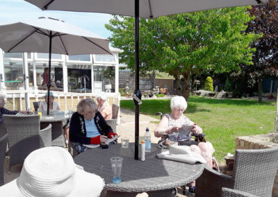 Residents enjoying reading outside in the garden at Silverpoint Court