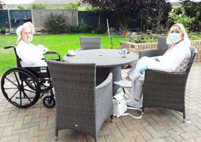 Silverpoint Court Residential Care Home resident enjoying a socially distant visit with a loved one on the patio in the garden