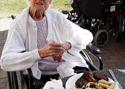 Resident enjoying a plate of BBQ food in the garden at Silverpoint Court